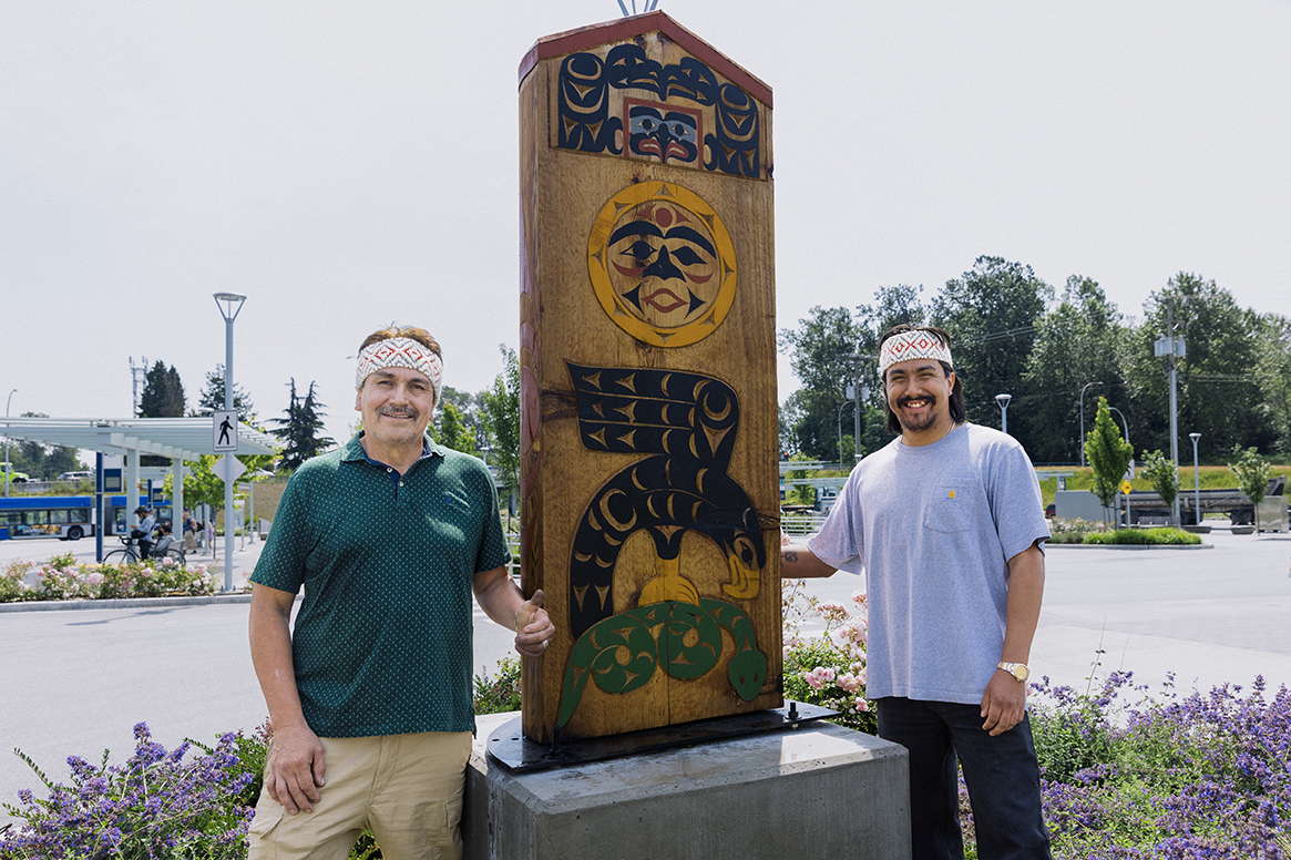 Matthew and Liam Baker stand in front of their artwork titled 'Welcome to ch’ich’exwi7kw'